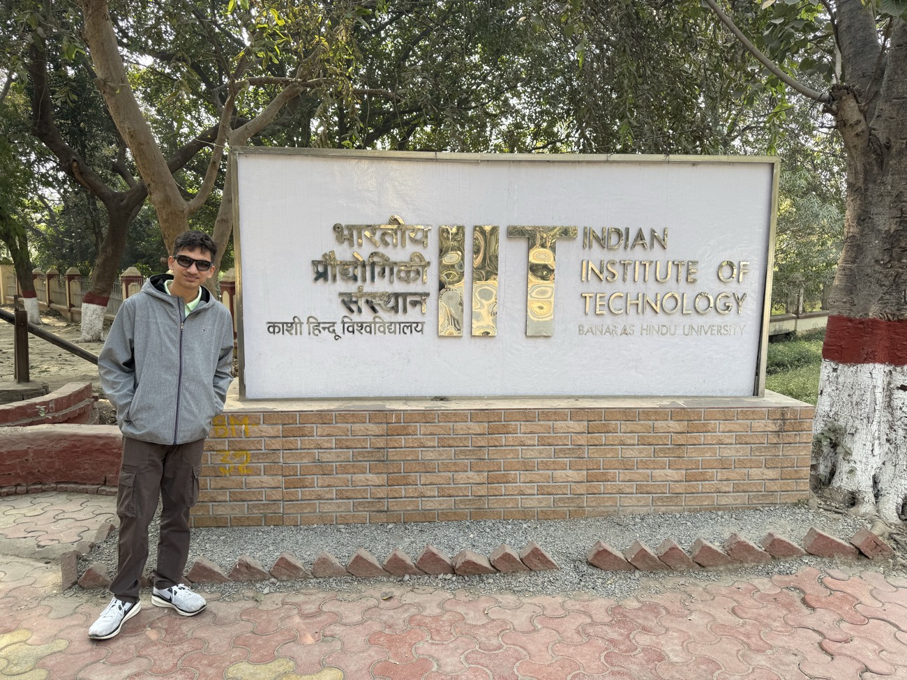 Hemish Thanki standing beside the Indian Institute of Technology (BHU) Varanasi campus sign.